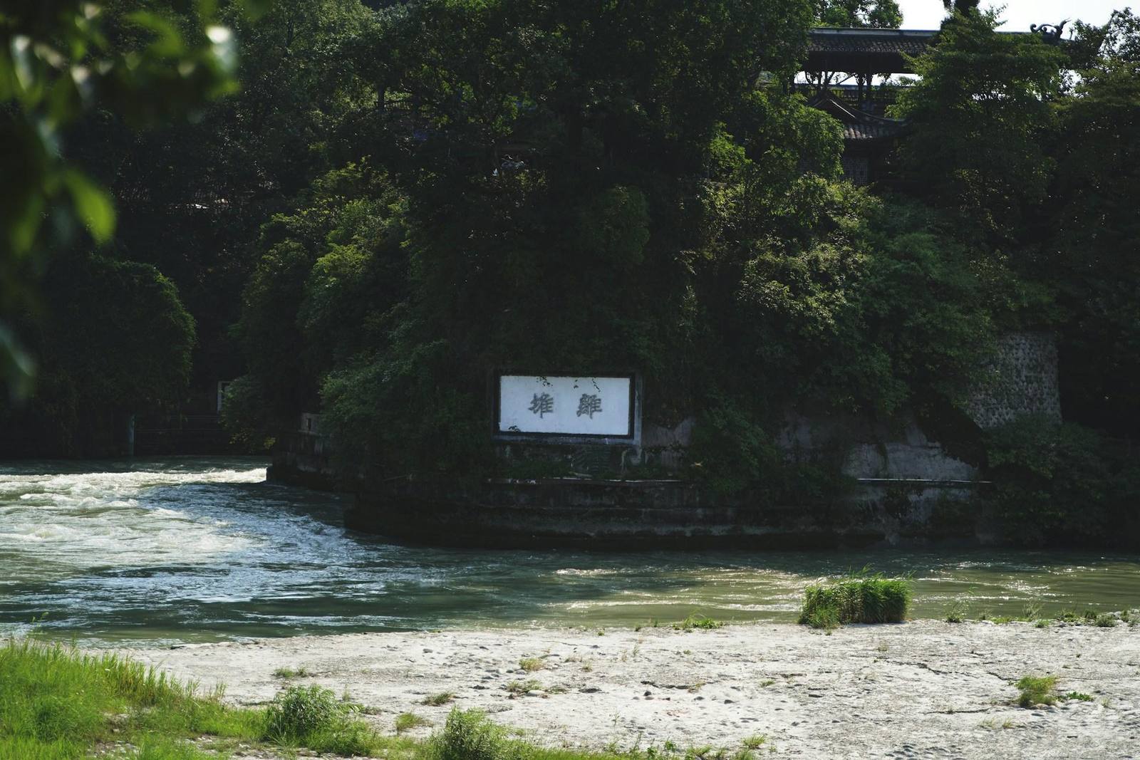 The Minjiang rushing past the wooded Lidui mound at Dujiangyan, below the temple