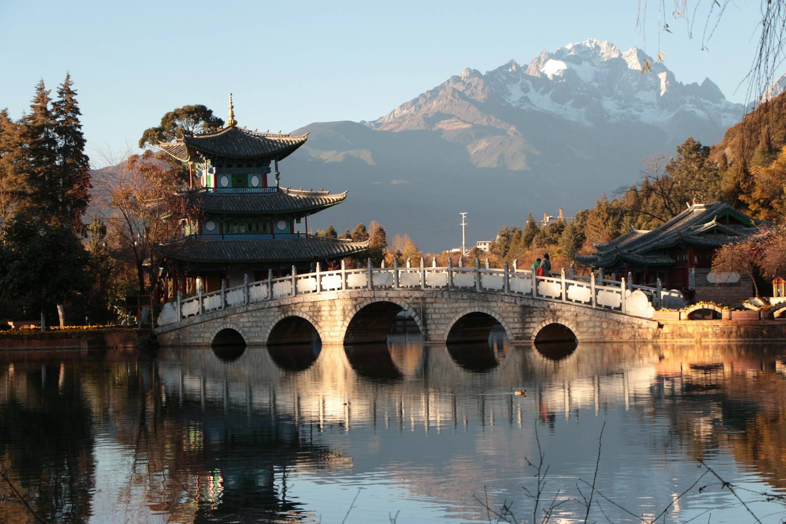 Black Dragon Pool at dawn: five-arch bridge, pavilion, and the Jade Dragon Snow Mountain reflected