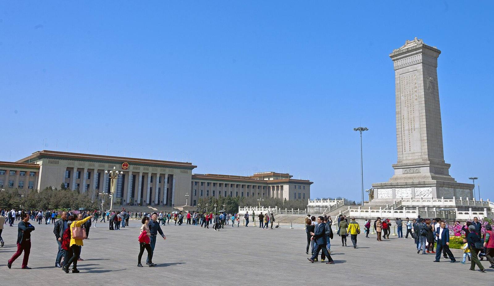 Visitors crossing the open expanse of Tiananmen Square with the Monument and the Great Hall beyond